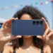 Young lady holding a dark navy Samsung S25 FE at a festival.
