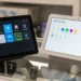 Google Nest Hub Max and Amazon Echo Show 15 displayed catacornered on a glass retail shelf