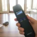 Hand holding a black anti spy scanner in a sunlit messy living room during a security sweep