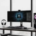 A modern black gaming PC and ultrawide monitor displaying an AI model graphic on a wooden desk.