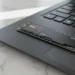 Samsung 990 Pro 2TB NVMe SSD sitting on a black laptop trackpad for a high speed storage upgrade