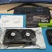 A Gigabyte GeForce RTX 3060 graphics card unboxed on a blue desk mat with its retail box, manual, and a small precision screwdriver kit.